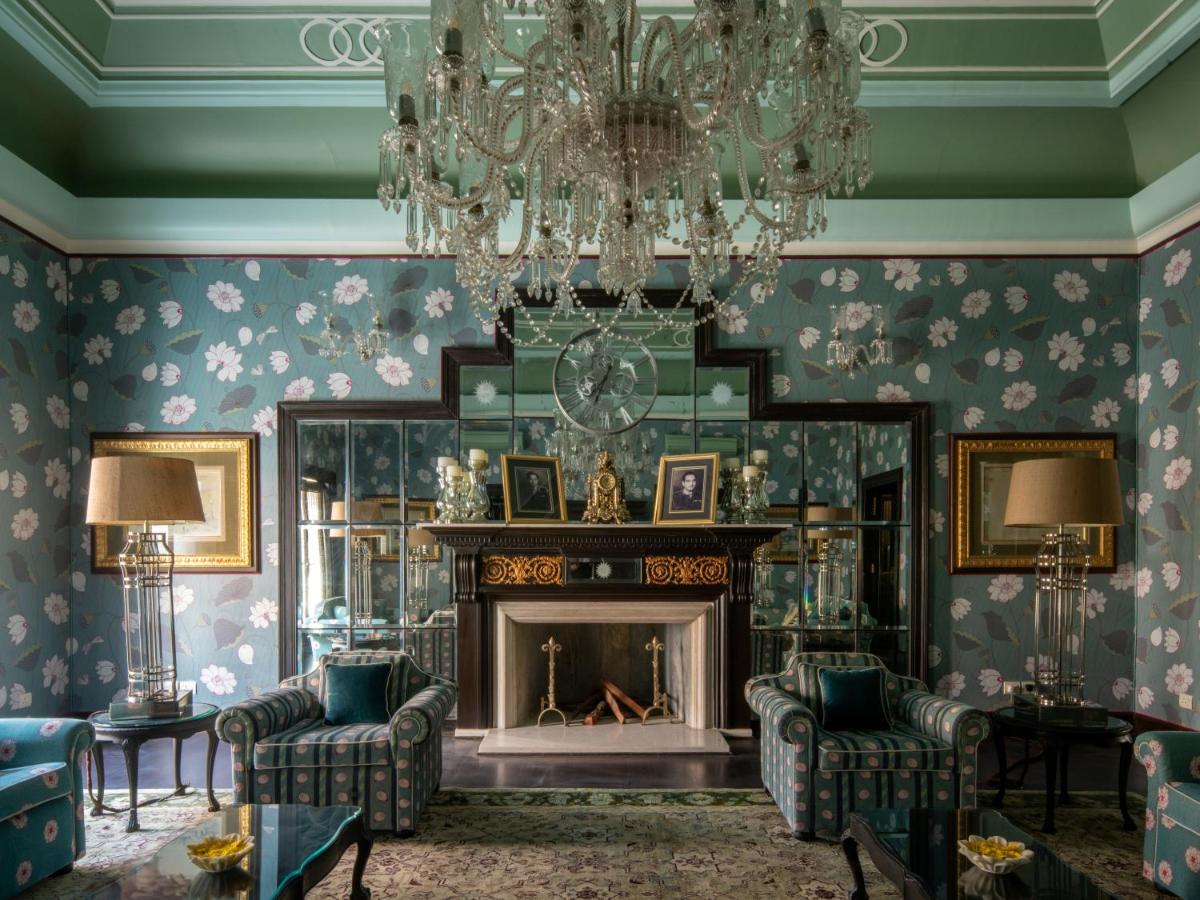a living room with a fireplace and a chandelier at Rajmahal Palace RAAS in Jaipur