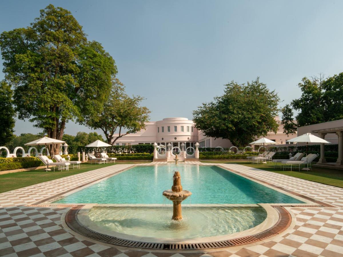 a pool with a fountain in front of a building at Rajmahal Palace RAAS in Jaipur