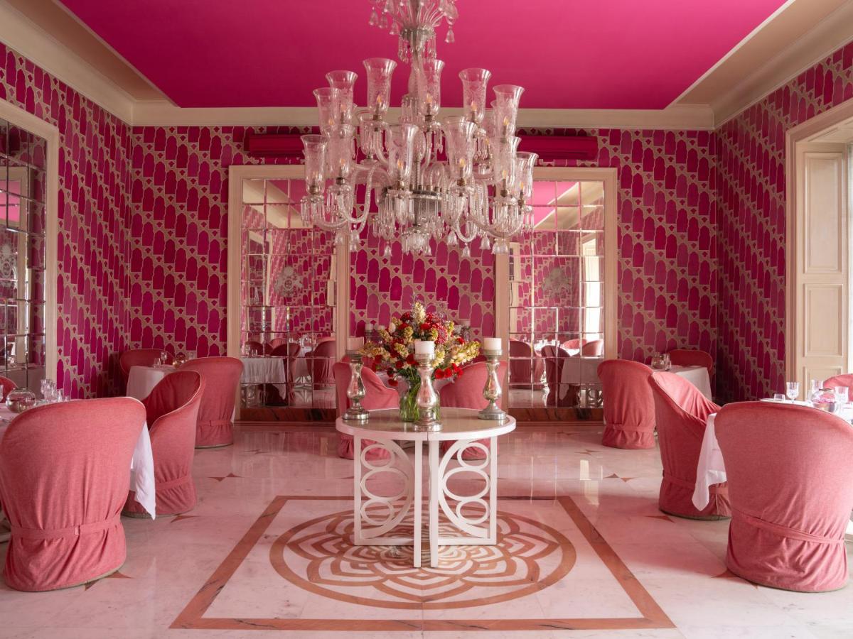 a pink room with a table and a chandelier at Rajmahal Palace RAAS in Jaipur