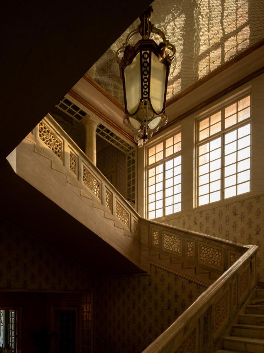 a staircase in a building with windows and a chandelier at Rajmahal Palace RAAS in Jaipur