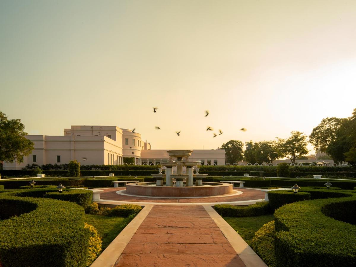 a fountain in a park with birds flying in the sky at Rajmahal Palace RAAS in Jaipur