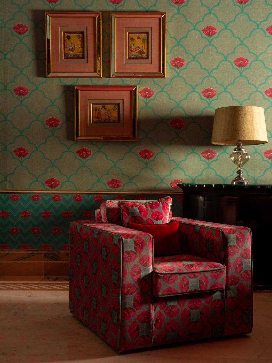 a living room with a red chair and a lamp at Rajmahal Palace RAAS in Jaipur