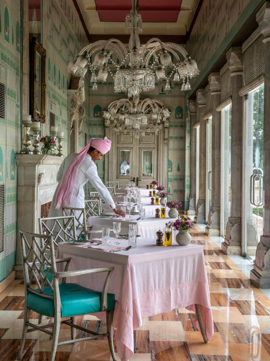 a chef in a dining room with a table at Rajmahal Palace RAAS in Jaipur