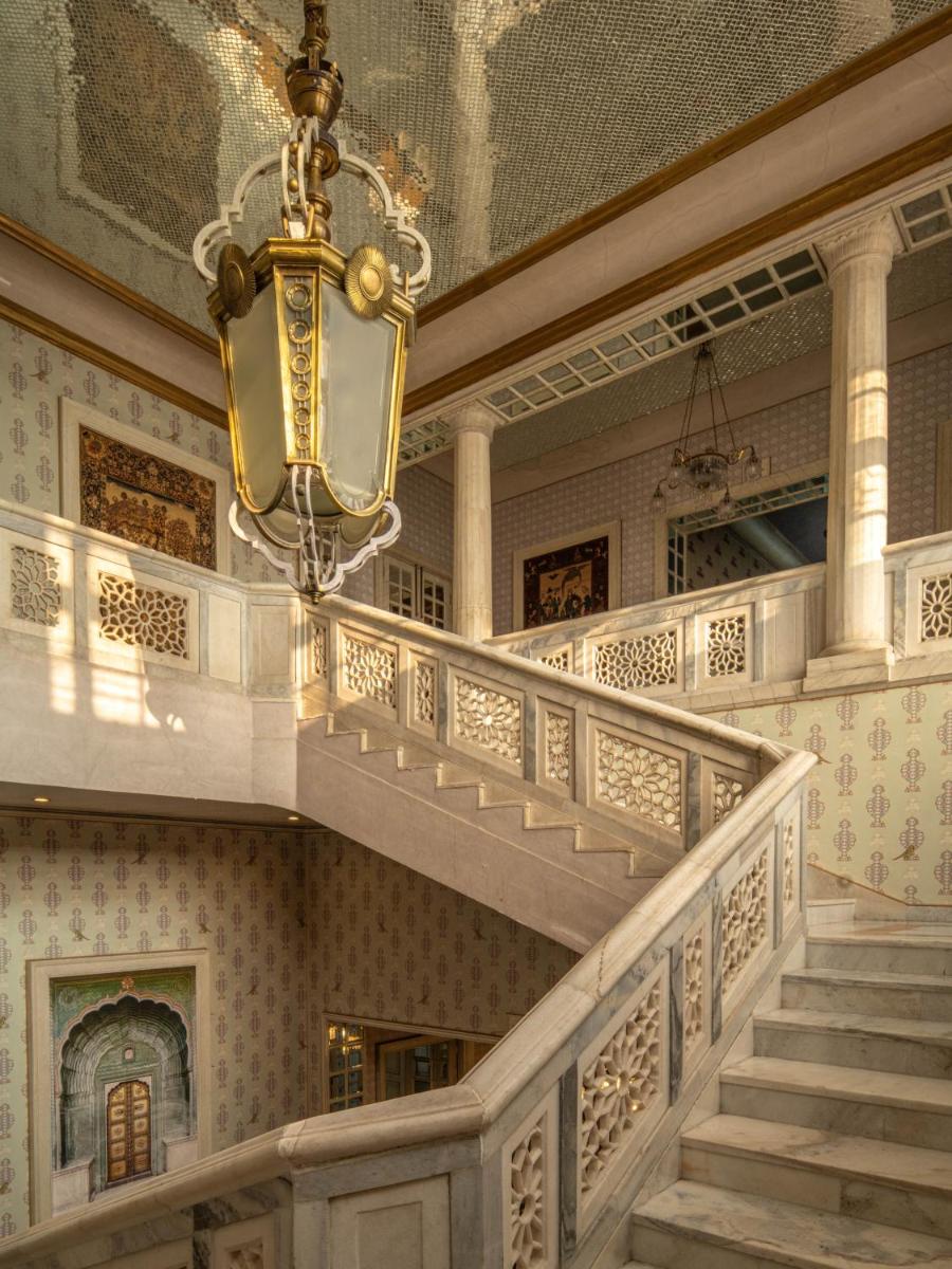 a chandelier hanging from a ceiling in a building with stairs at Rajmahal Palace RAAS in Jaipur