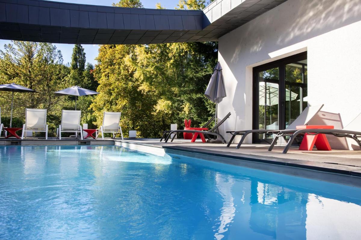 - une piscine avec des chaises et des parasols à côté d'une maison dans l'établissement L'Aubinière Hôtel Restaurant & Spa, à Saint-Ouen-les-Vignes
