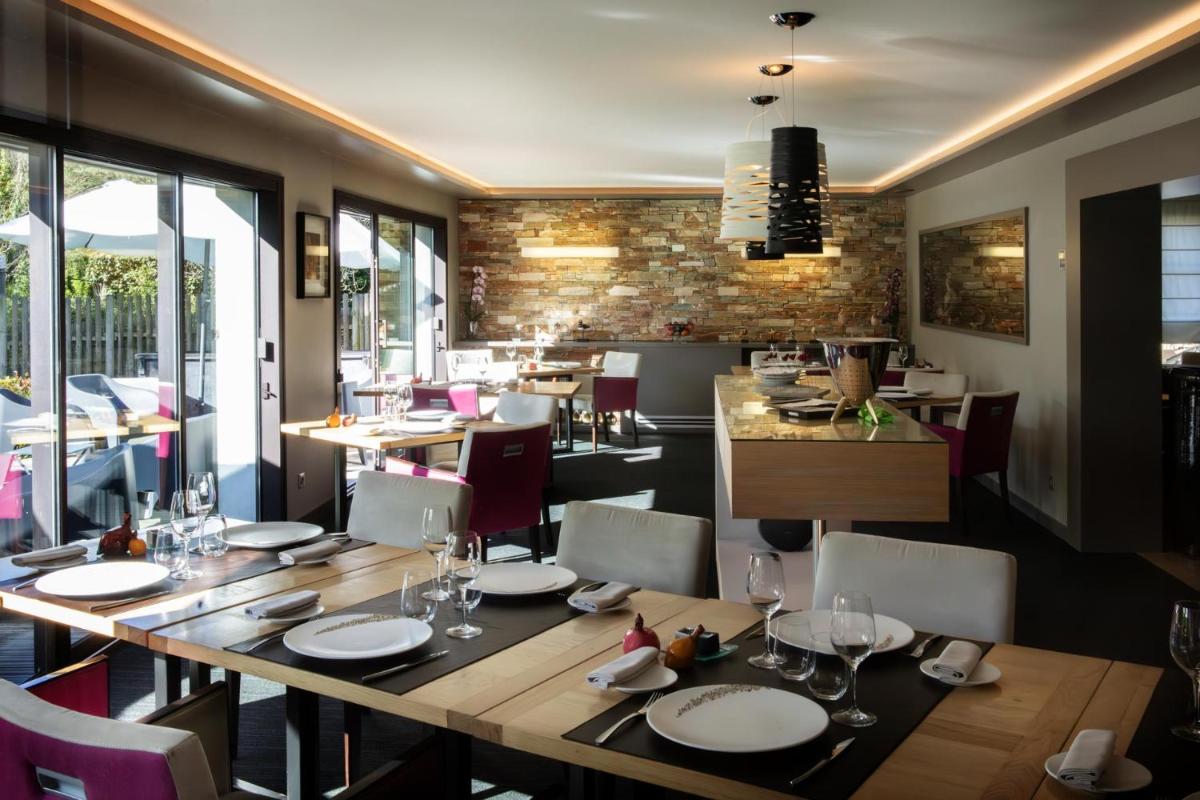 un restaurant avec une grande table et des chaises en bois dans l'établissement L'Aubinière Hôtel Restaurant & Spa, à Saint-Ouen-les-Vignes