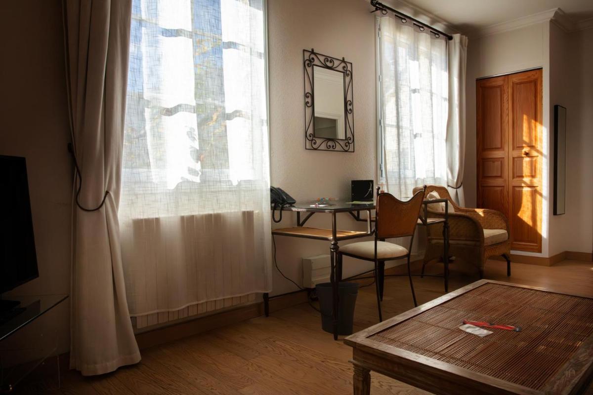 d'un salon avec un bureau, une chaise et une fenêtre. dans l'établissement L'Aubinière Hôtel Restaurant & Spa, à Saint-Ouen-les-Vignes