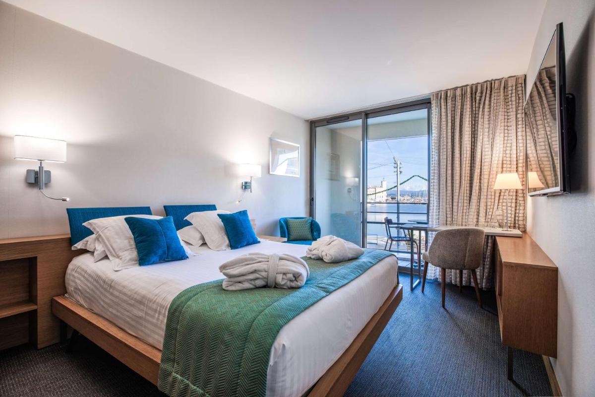 une chambre d'hôtel avec un lit recouvert d'oreillers bleus dans l'établissement Best Western Premier Hôtel du Vieux-Port, à La Ciotat