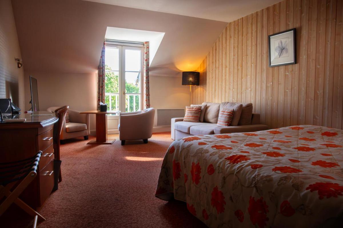 une chambre d'hôtel avec un lit et un canapé dans l'établissement L'Aubinière Hôtel Restaurant & Spa, à Saint-Ouen-les-Vignes