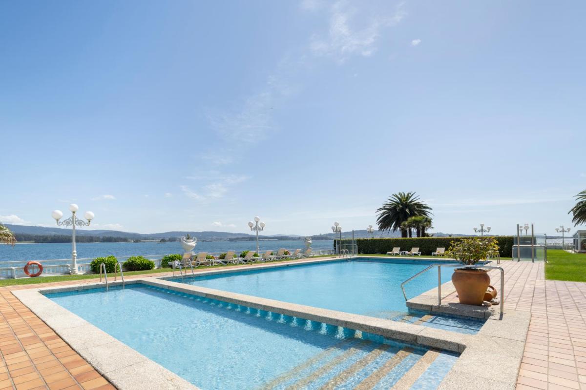 una gran piscina al lado de un cuerpo de agua en Eurostars Louxo Talaso, en Isla de la Toja