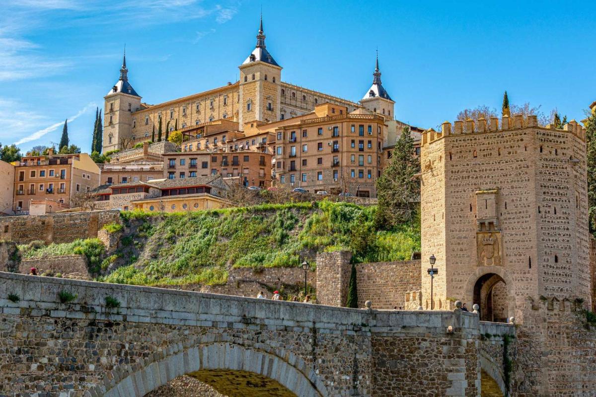un gran castillo en una colina con un puente en Áurea Toledo by Eurostars Hotel company, en Toledo