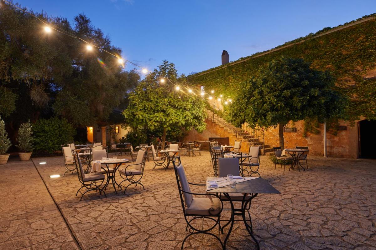 Un patio al aire libre con mesas, sillas y luces. en Zoetry Mallorca Wellness & Spa, en Llucmajor