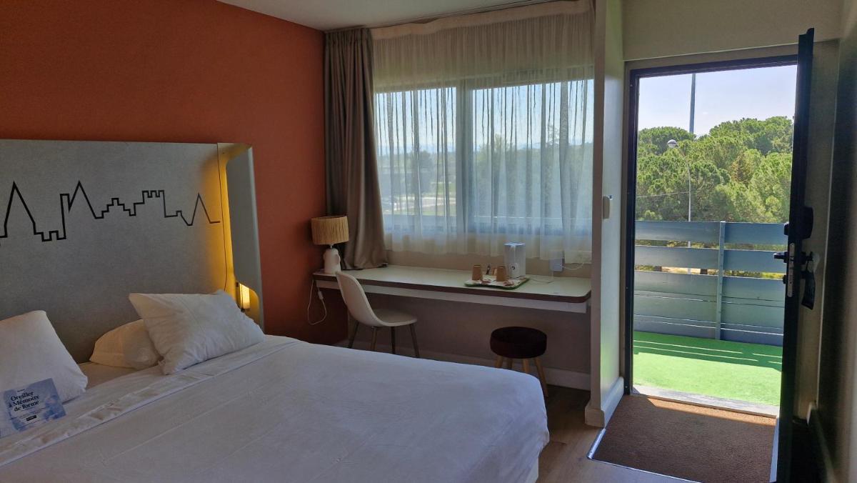 une chambre avec un lit, un bureau et une fenêtre dans l'établissement Kyriad Carcassonne - Aéroport, à Carcassonne 99 autres photos