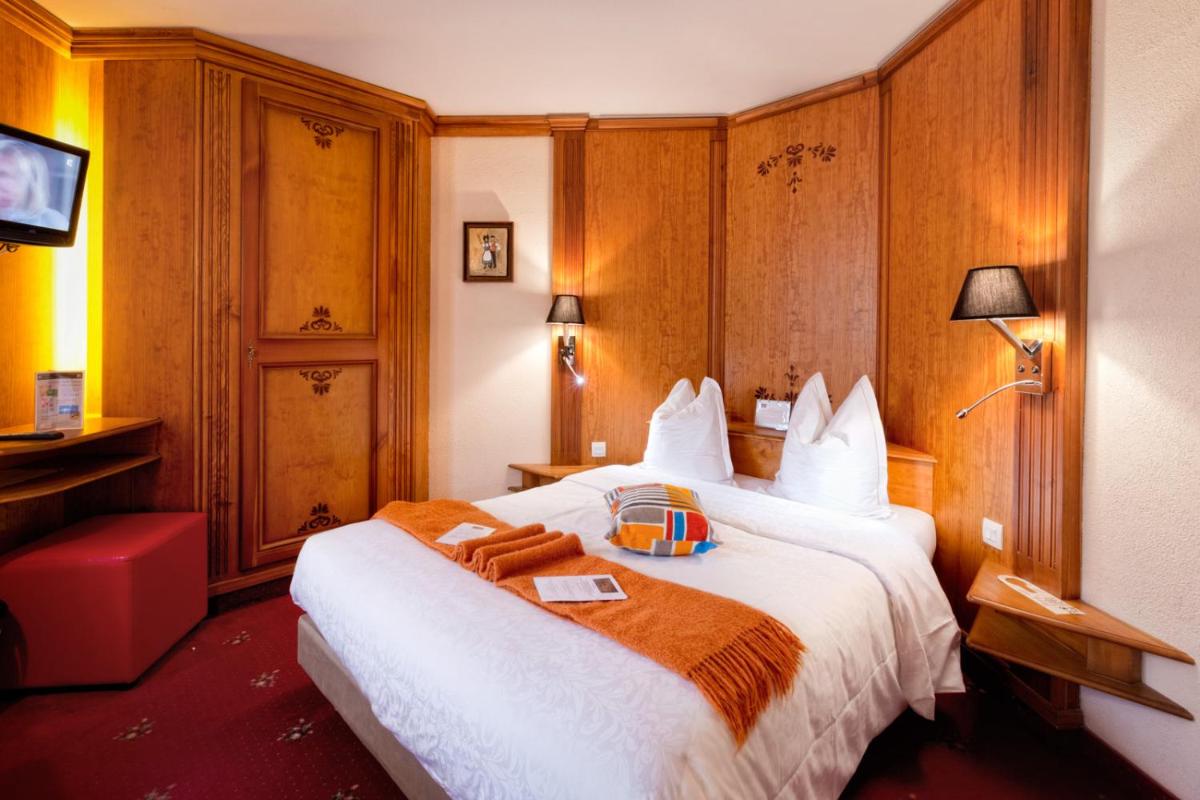 une chambre d'hôtel avec un lit et une télévision dans l'établissement Hotel - Restaurant Le Cerf & Spa, à Marlenheim