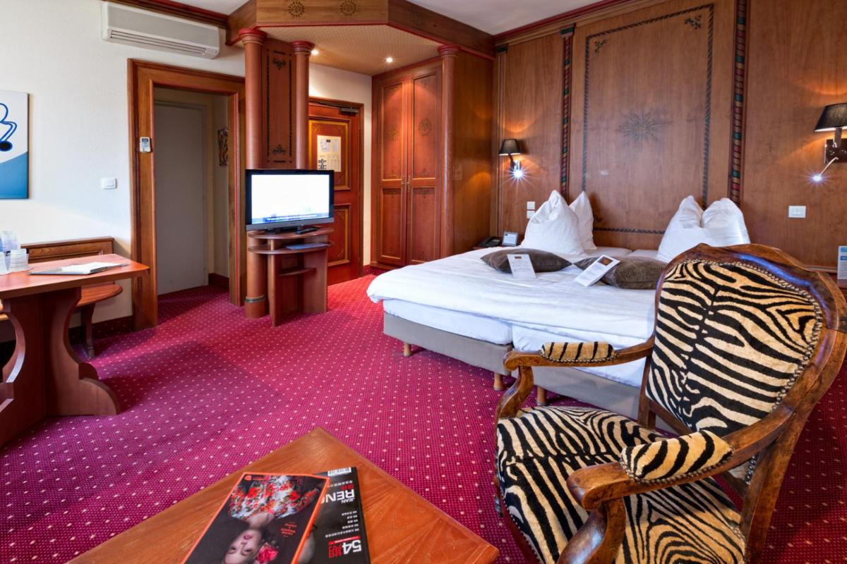 une chambre d'hôtel avec un lit et une télévision dans l'établissement Hotel - Restaurant Le Cerf & Spa, à Marlenheim