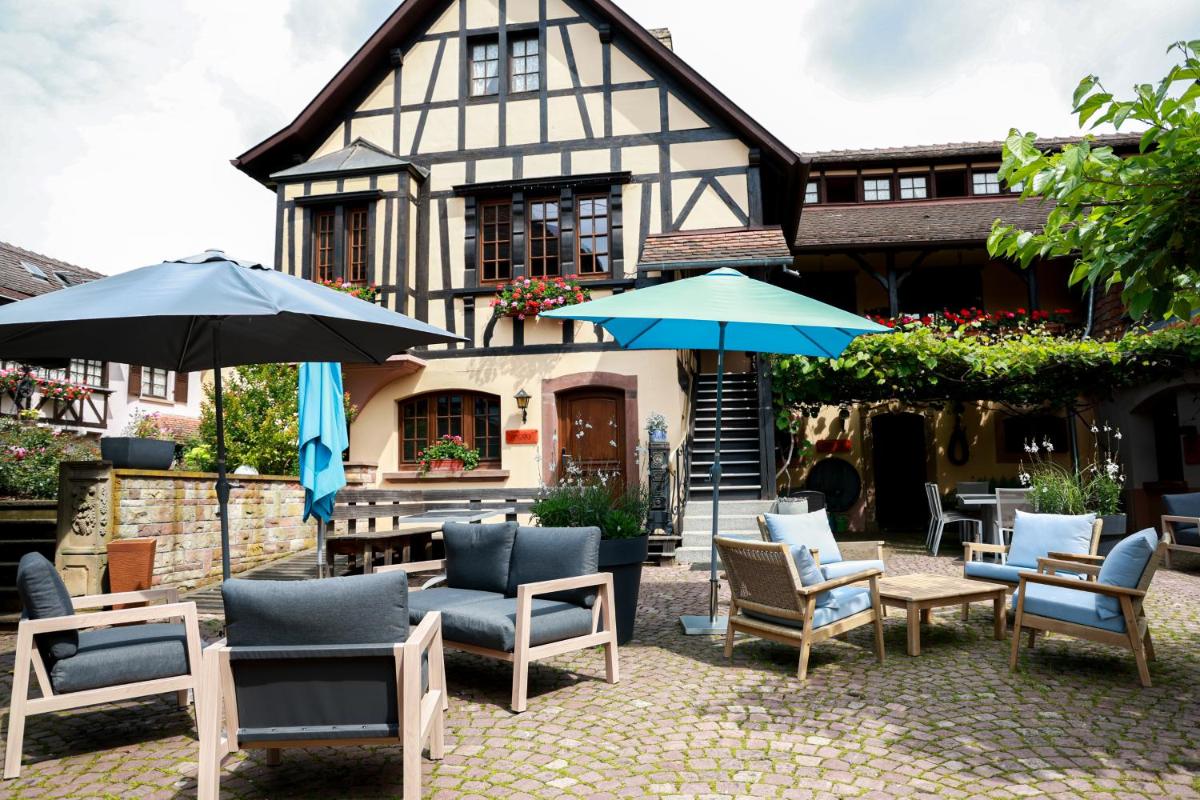 un groupe de chaises et de parasols devant une maison dans l'établissement Hotel - Restaurant Le Cerf & Spa, à Marlenheim
