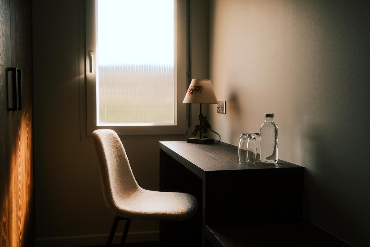 un bureau avec une bouteille et une chaise à côté d'une fenêtre dans l'établissement Hotel Restaurant des Vosges, à Birkenwald