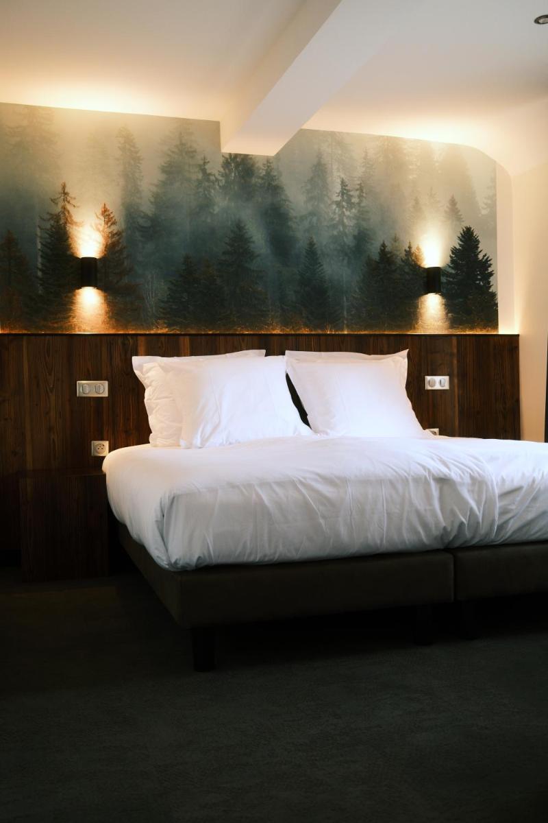 un lit avec des draps blancs et des oreillers dans une chambre dans l'établissement Hotel Restaurant des Vosges, à Birkenwald