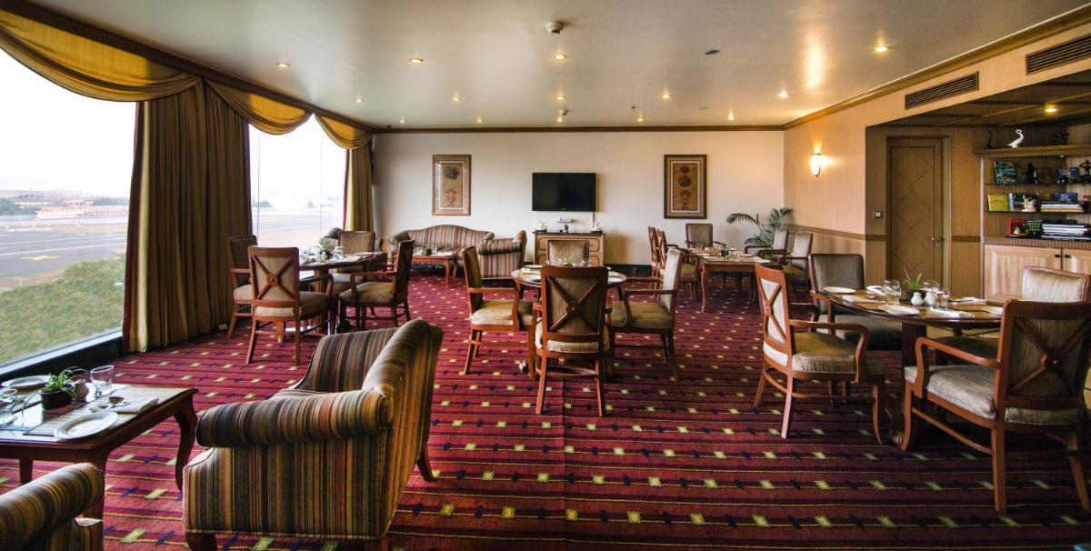 a restaurant with tables and chairs and a large window at The Orchid Hotel Mumbai Vile Parle in Mumbai