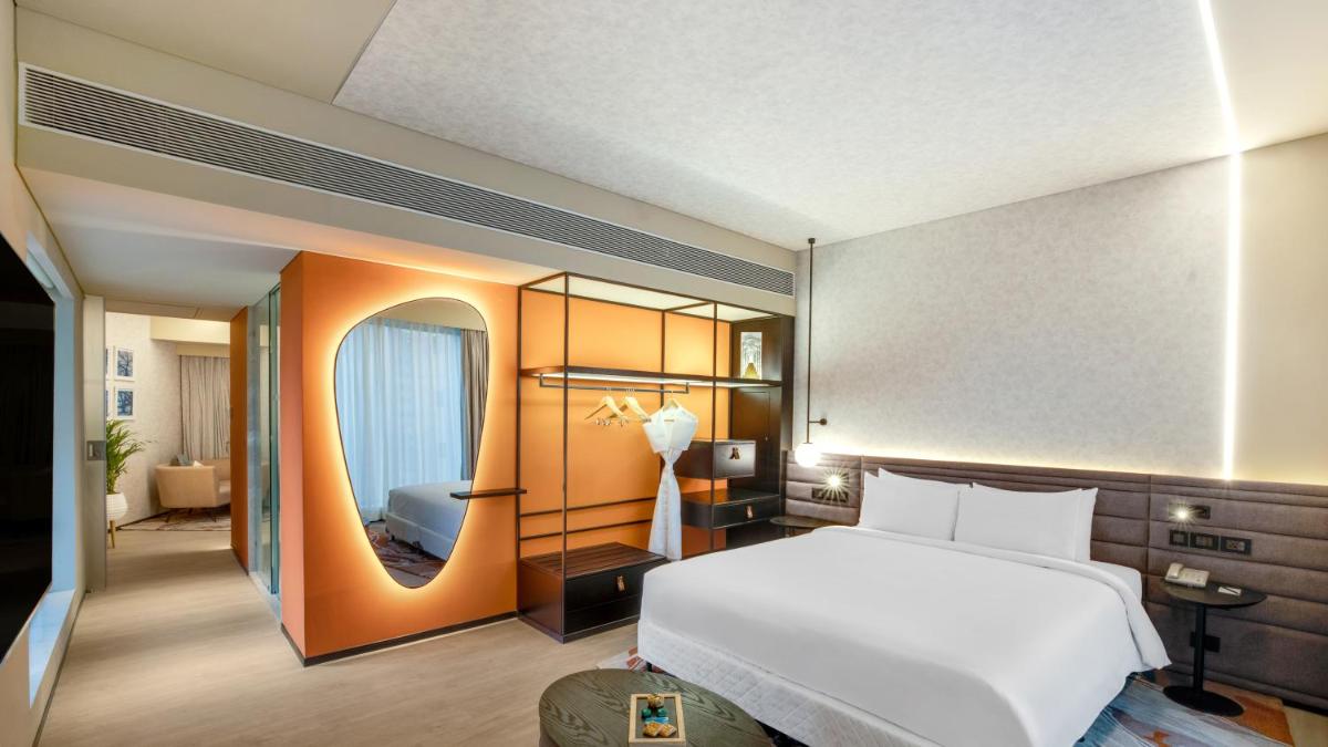 a bedroom with a large white bed and a mirror at Novotel Pune Viman Nagar Road in Pune