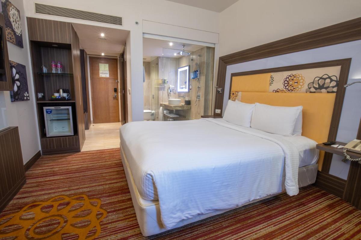 a bedroom with a large white bed and a bathroom at Novotel Pune Viman Nagar Road in Pune