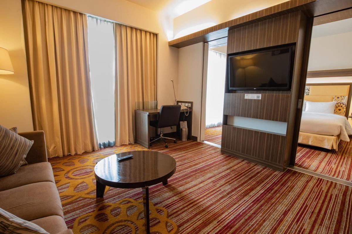 a hotel room with a bed and a television at Novotel Pune Viman Nagar Road in Pune