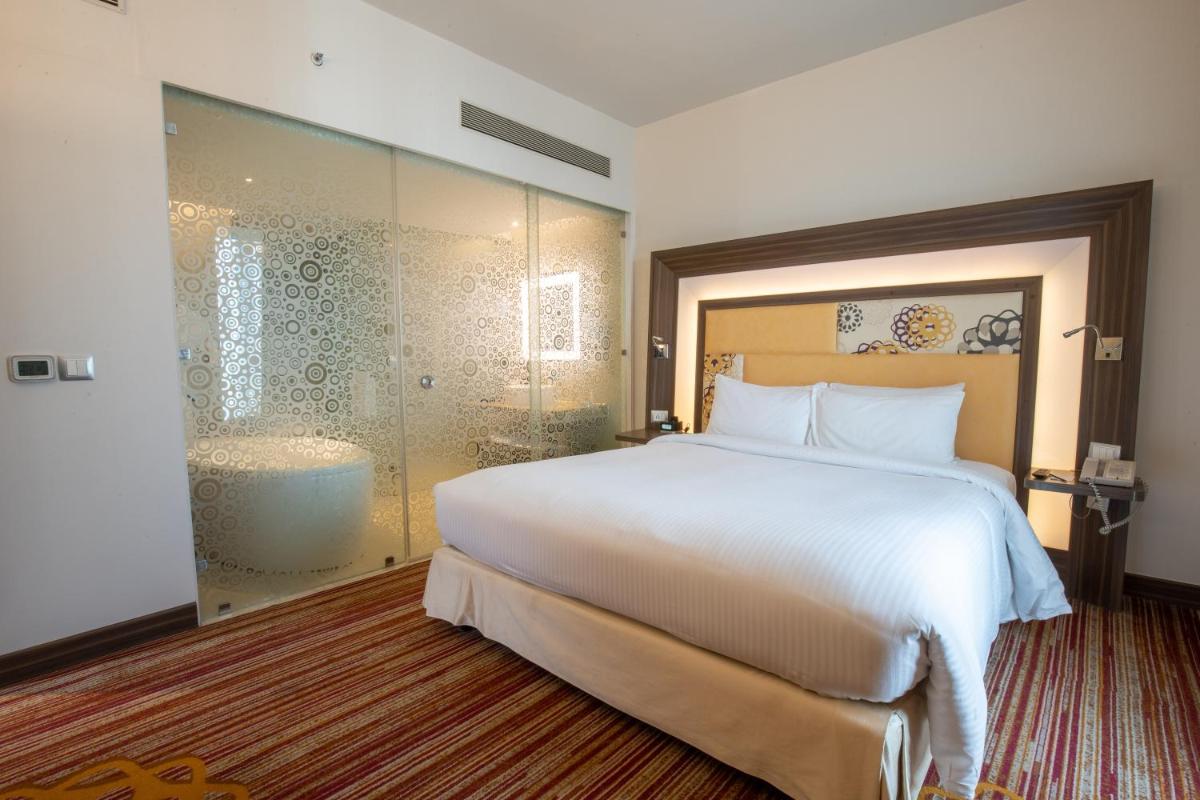 a bedroom with a large white bed and a shower at Novotel Pune Viman Nagar Road in Pune