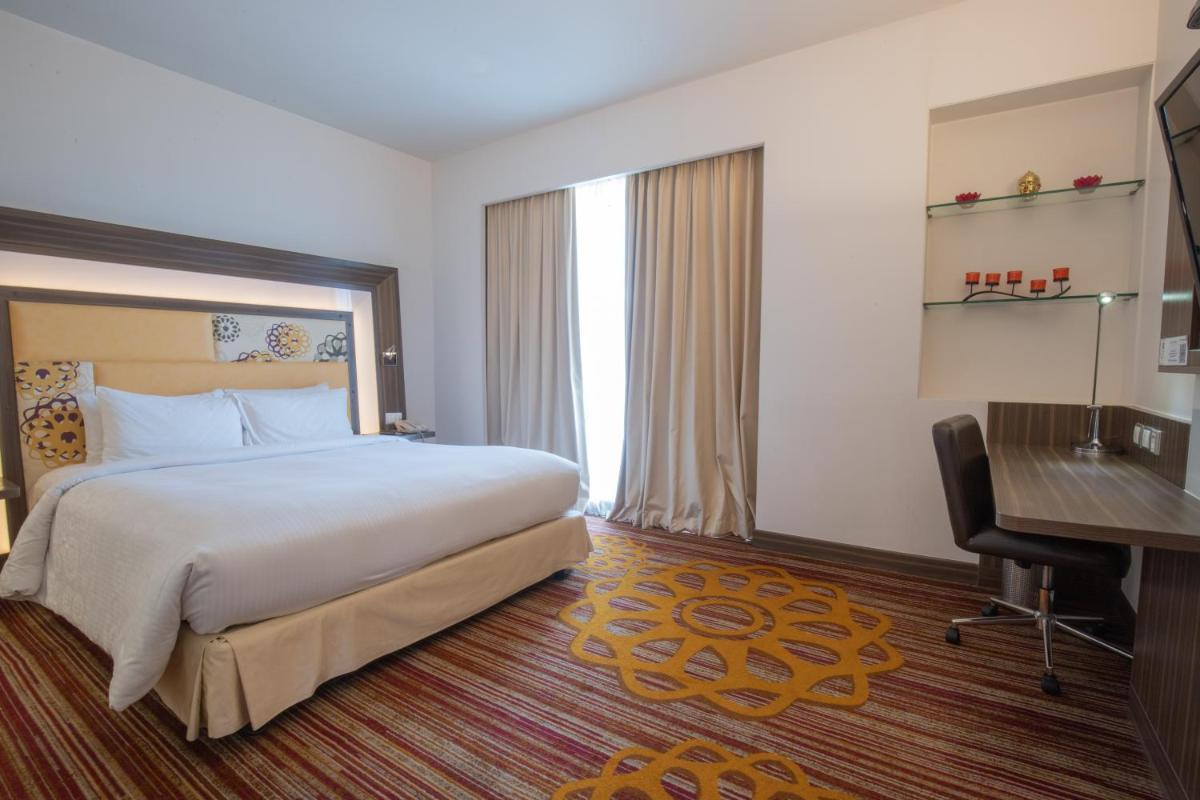 a hotel room with a bed and a desk at Novotel Pune Viman Nagar Road in Pune