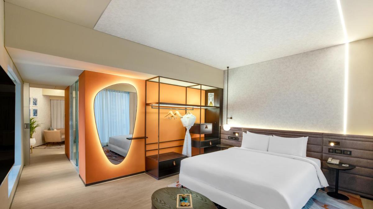 a bedroom with a large white bed and a mirror at Novotel Pune Viman Nagar Road in Pune