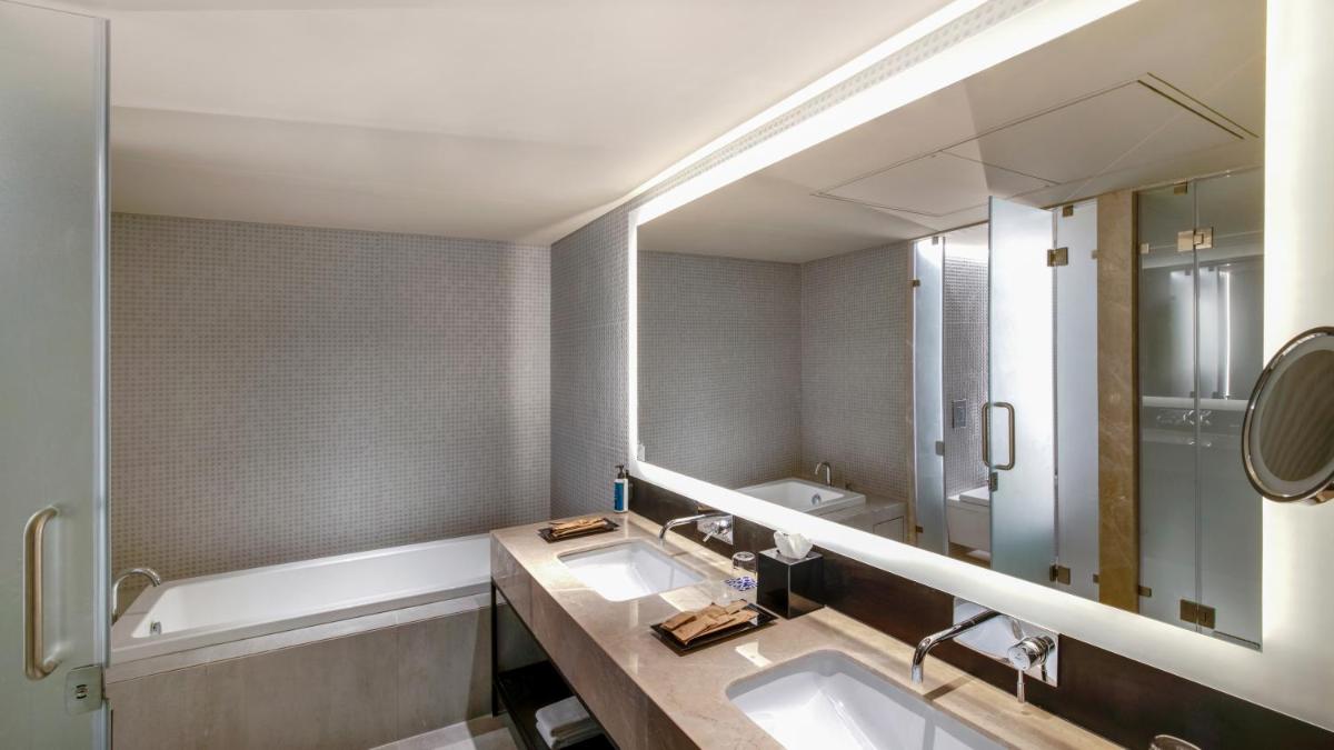 a bathroom with two sinks and a tub and a mirror at Novotel Pune Viman Nagar Road in Pune