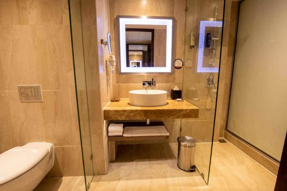 a bathroom with a sink and a mirror and a toilet at Novotel Pune Viman Nagar Road in Pune