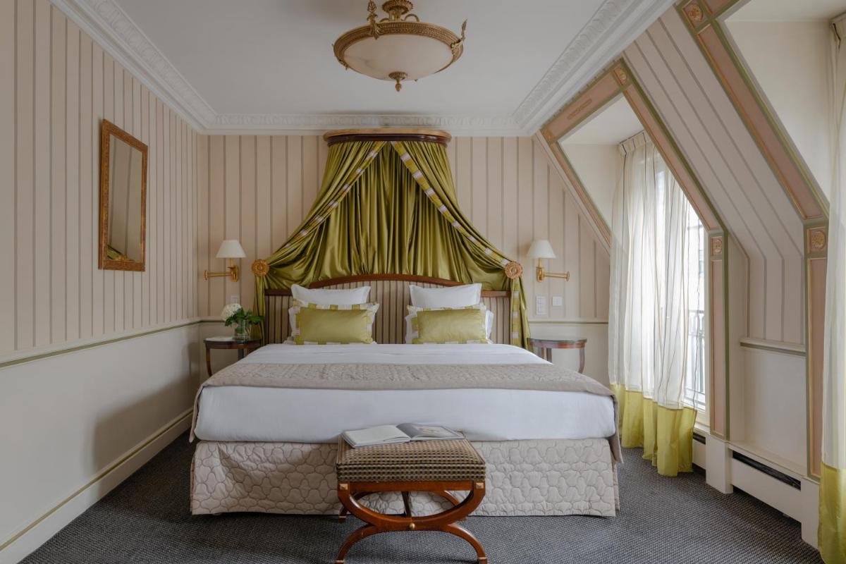 une chambre avec un grand lit à baldaquin dans l'établissement Hôtel Napoleon Paris, à Paris