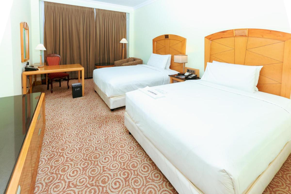 a hotel room with two beds and a desk at Le Royal Meridien Chennai in Chennai