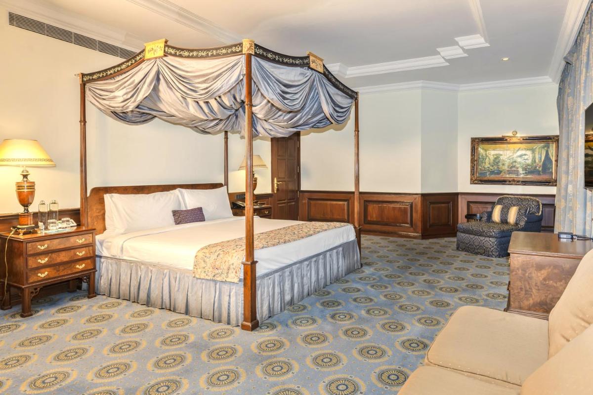 a bedroom with a canopy bed and a chair at Le Royal Meridien Chennai in Chennai