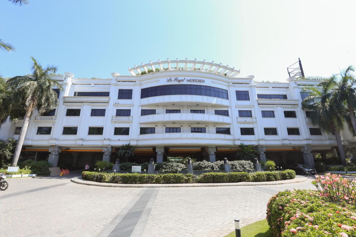 a large white building with palm trees in front of it at Le Royal Meridien Chennai in Chennai