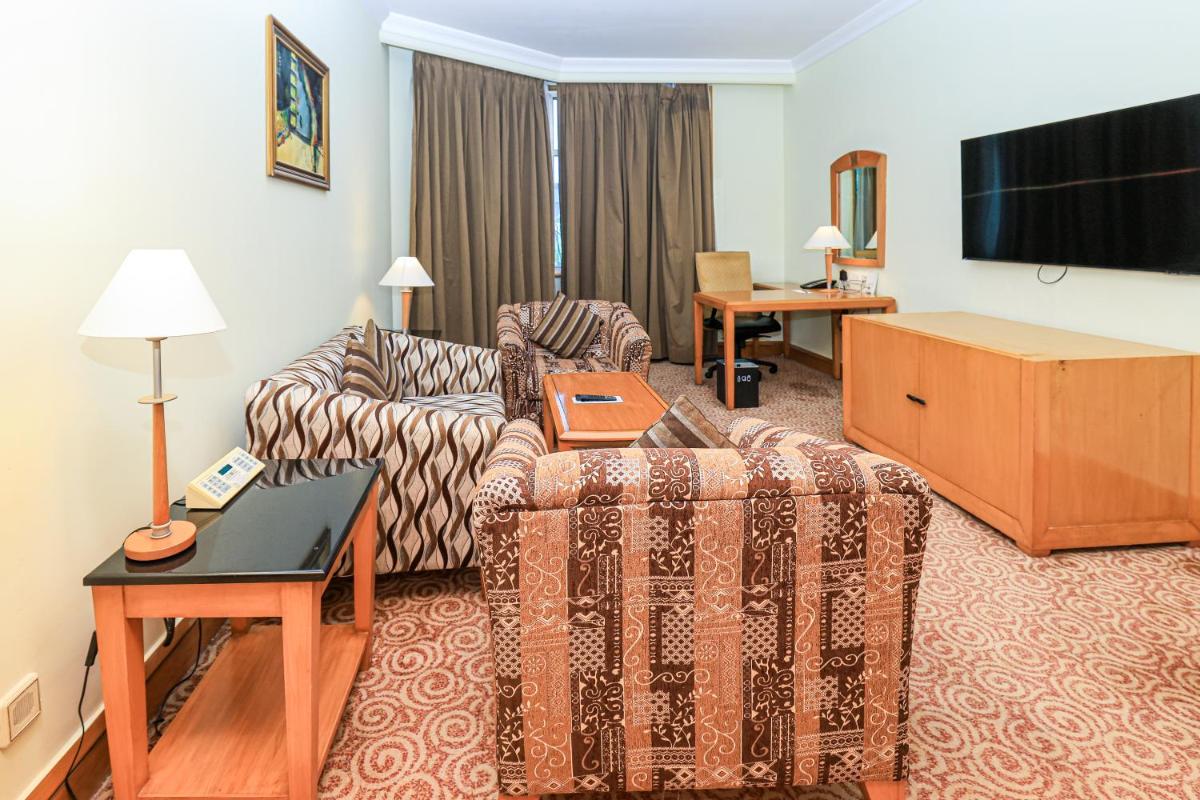 a living room with a couch and a flat screen tv at Le Royal Meridien Chennai in Chennai