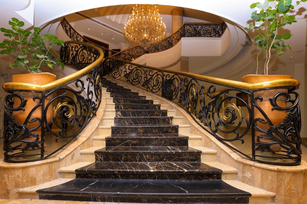 a spiral staircase with black marble and gold railings at Le Royal Meridien Chennai in Chennai