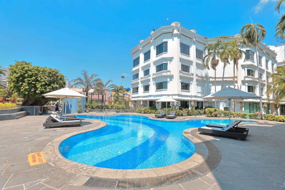 a swimming pool in front of a building at Le Royal Meridien Chennai in Chennai