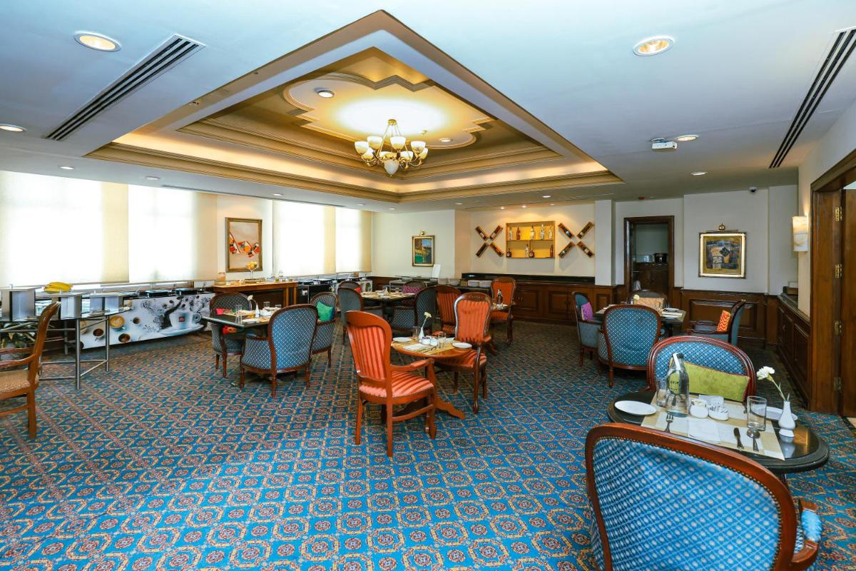 a restaurant with tables and chairs in a room at Le Royal Meridien Chennai in Chennai