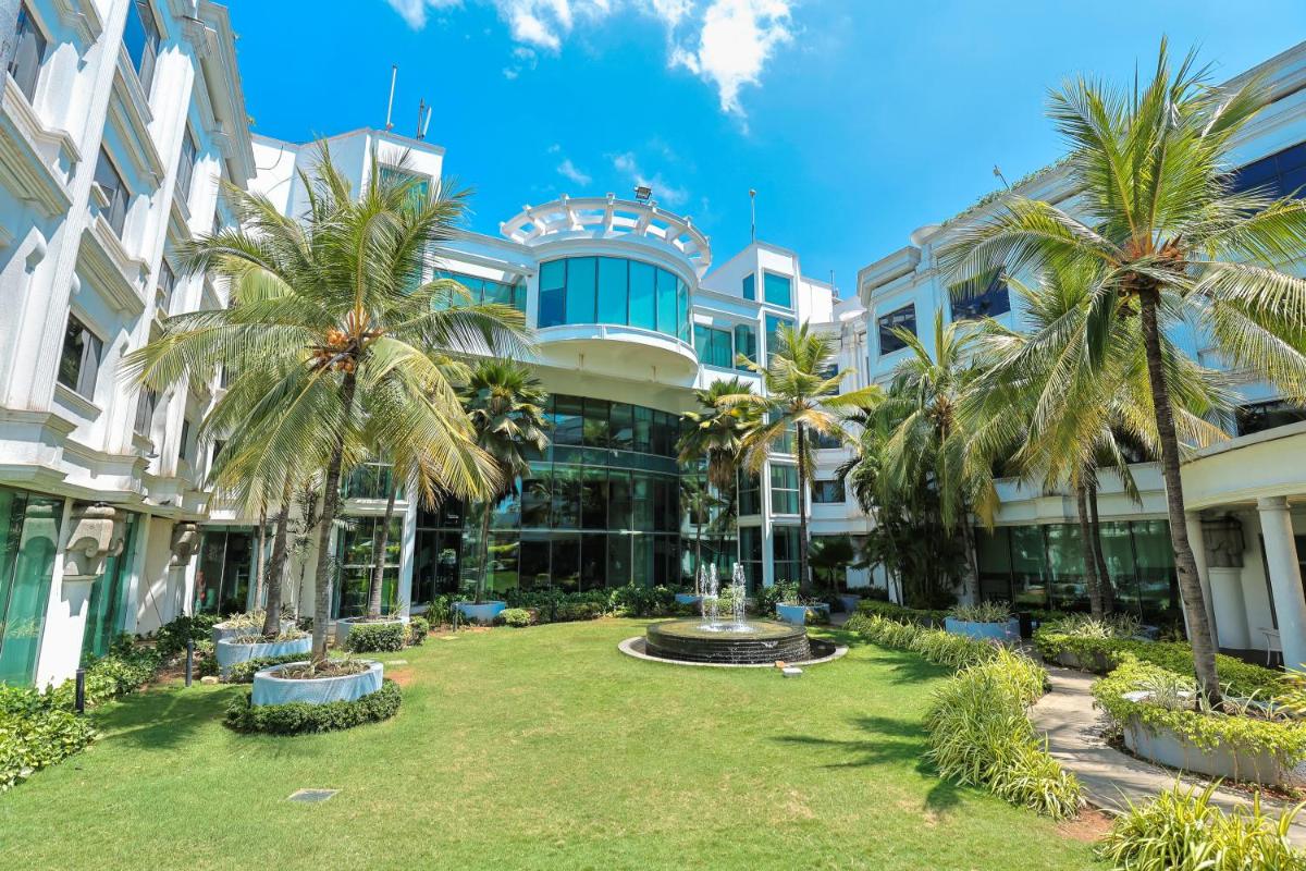 a building with palm trees in front of it at Le Royal Meridien Chennai in Chennai