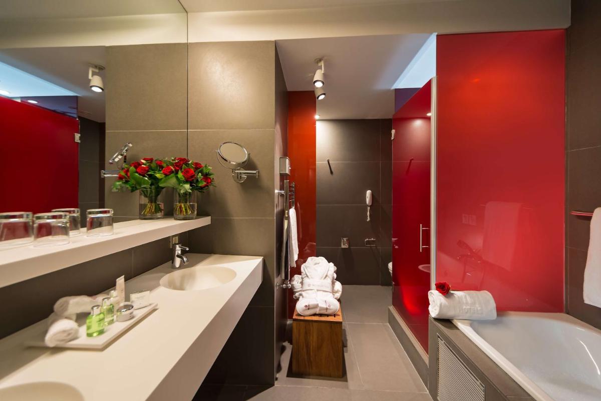 Un baño con dos lavabos, una ducha y una bañera. en NH Collection Barcelona Constanza, en Barcelona