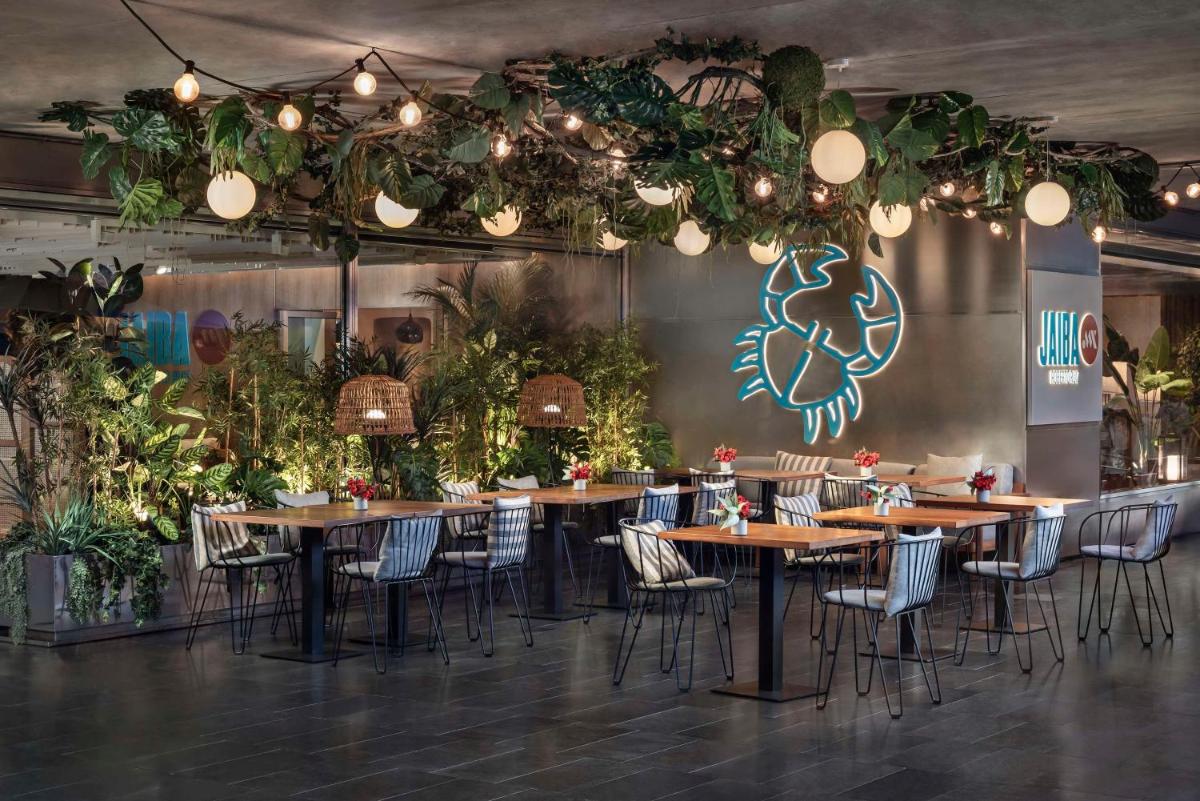 Un comedor con mesas y sillas y plantas. en NH Collection Barcelona Constanza, en Barcelona