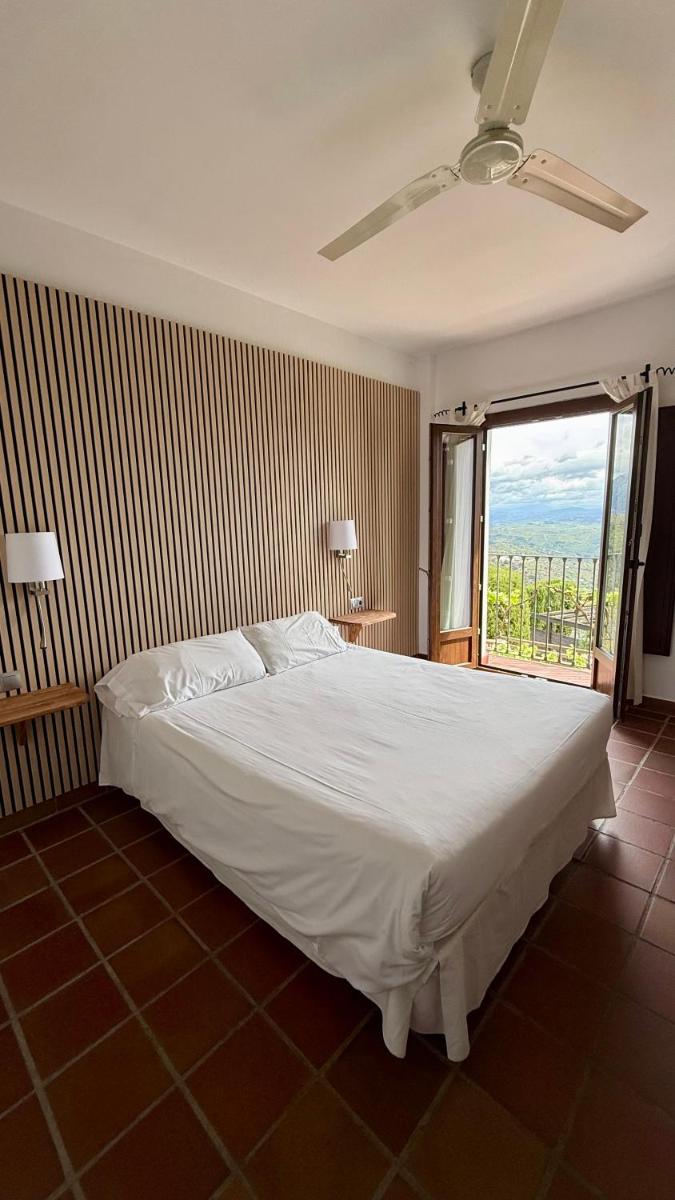 Un dormitorio con una gran cama blanca y una ventana. en Cerro de Hijar, en Tolox
