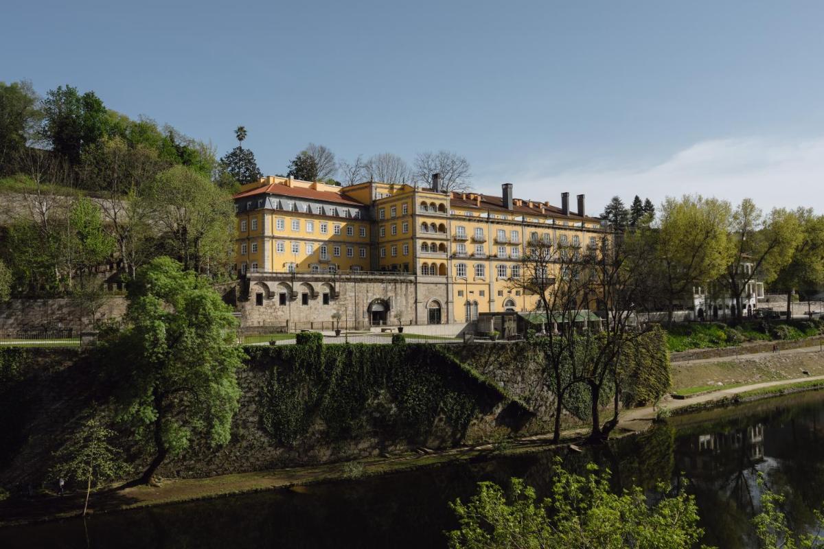 um grande edifício amarelo junto a um rio em Casa da Calçada em Amarante