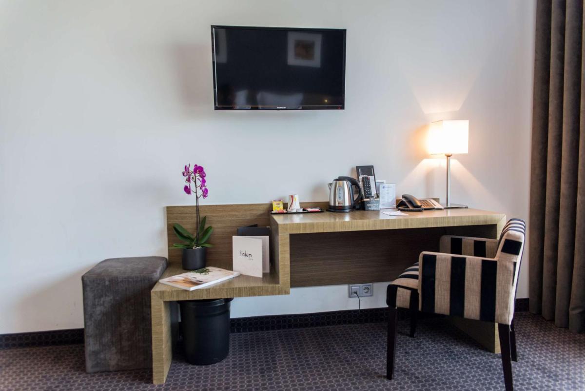 une chambre d'hôtel avec un bureau et une chaise dans l'établissement Best Western Hôtel De La Cité & Spa, à Guérande