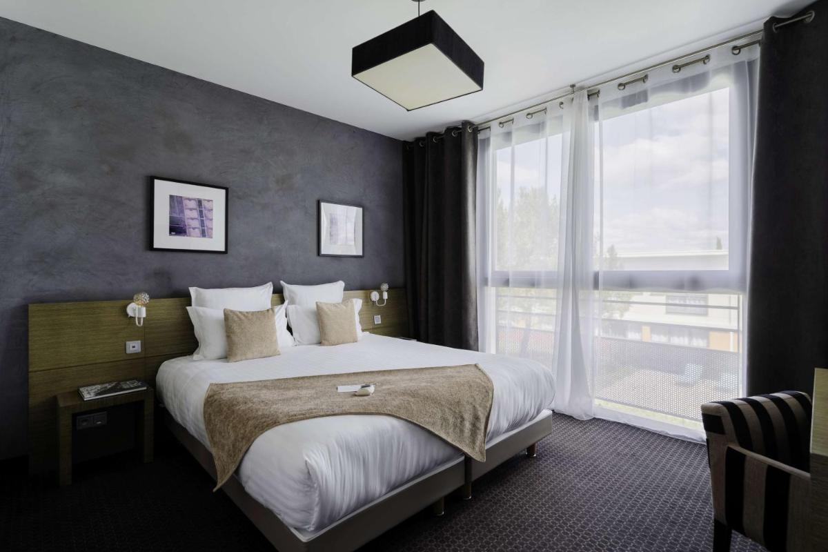 une chambre avec un grand lit et une grande fenêtre dans l'établissement Best Western Hôtel De La Cité & Spa, à Guérande
