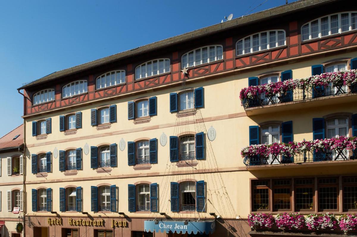 - un bâtiment avec des fenêtres et des boîtes de fleurs dans l'établissement Chez Jean, à Saverne