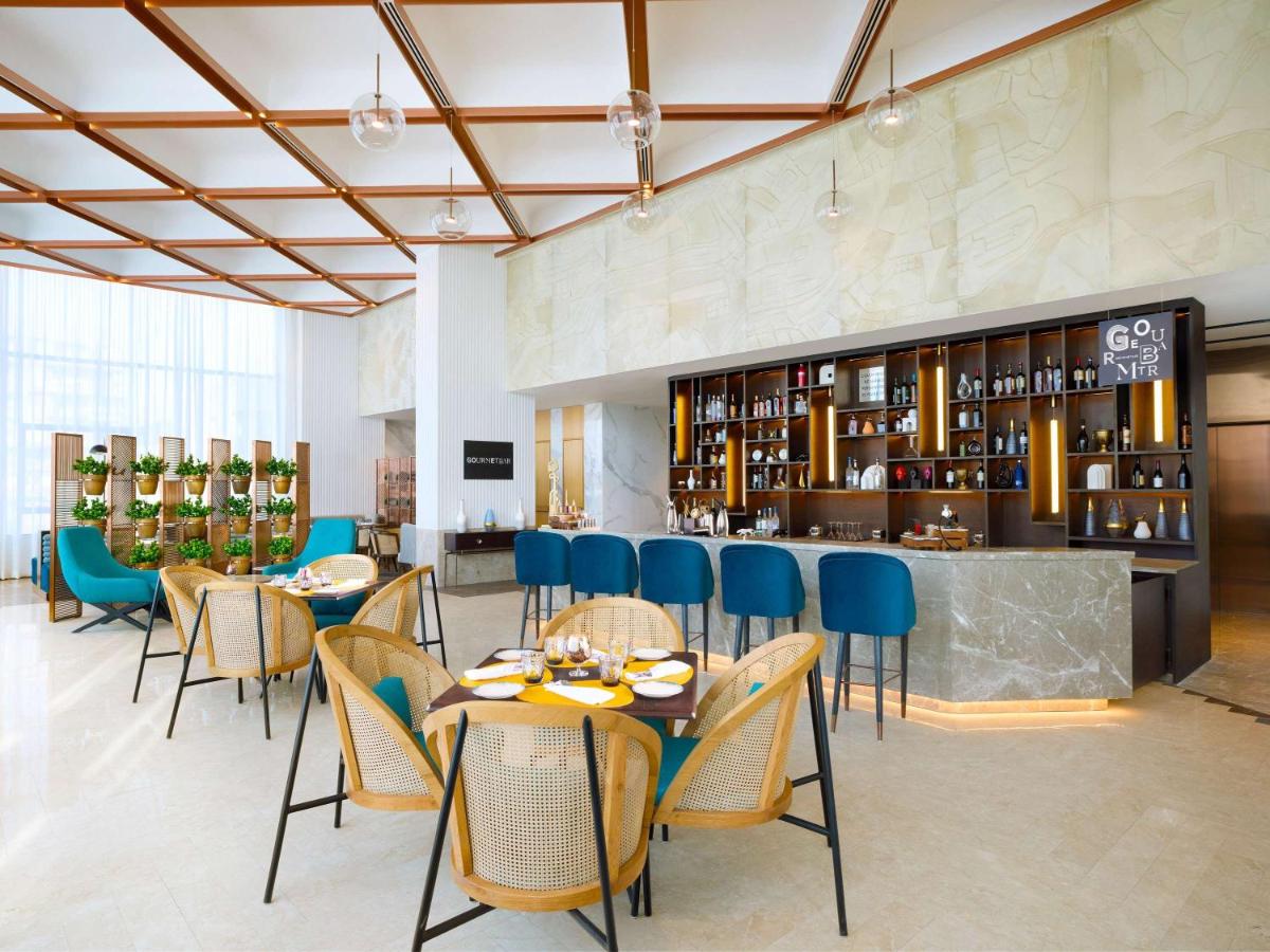 a restaurant with tables and chairs and a bar at Novotel New Delhi City Centre in New Delhi a restaurant with tables and chairs and a bar at Novotel New Delhi City Centre in New Delhi