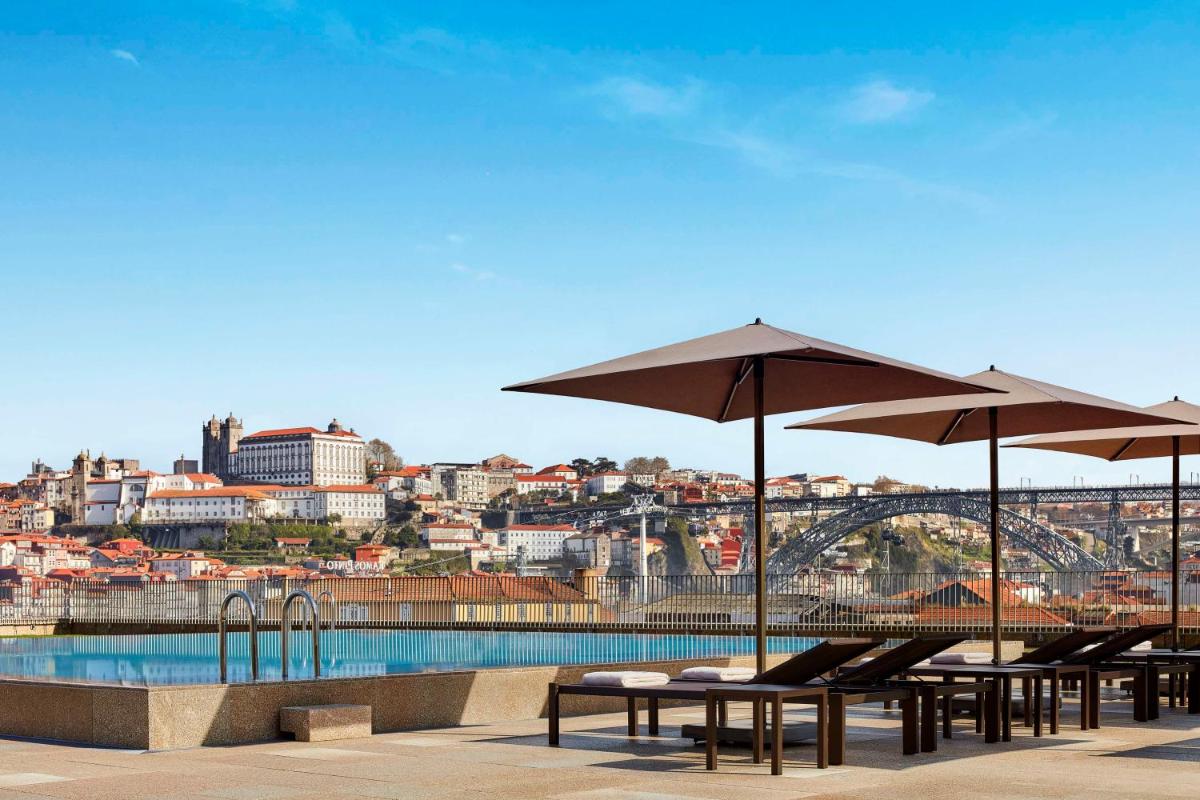 um grupo de mesas e guarda-sóis ao lado de uma piscina em Tivoli Kopke Porto Gaia Hotel em Vila Nova de Gaia