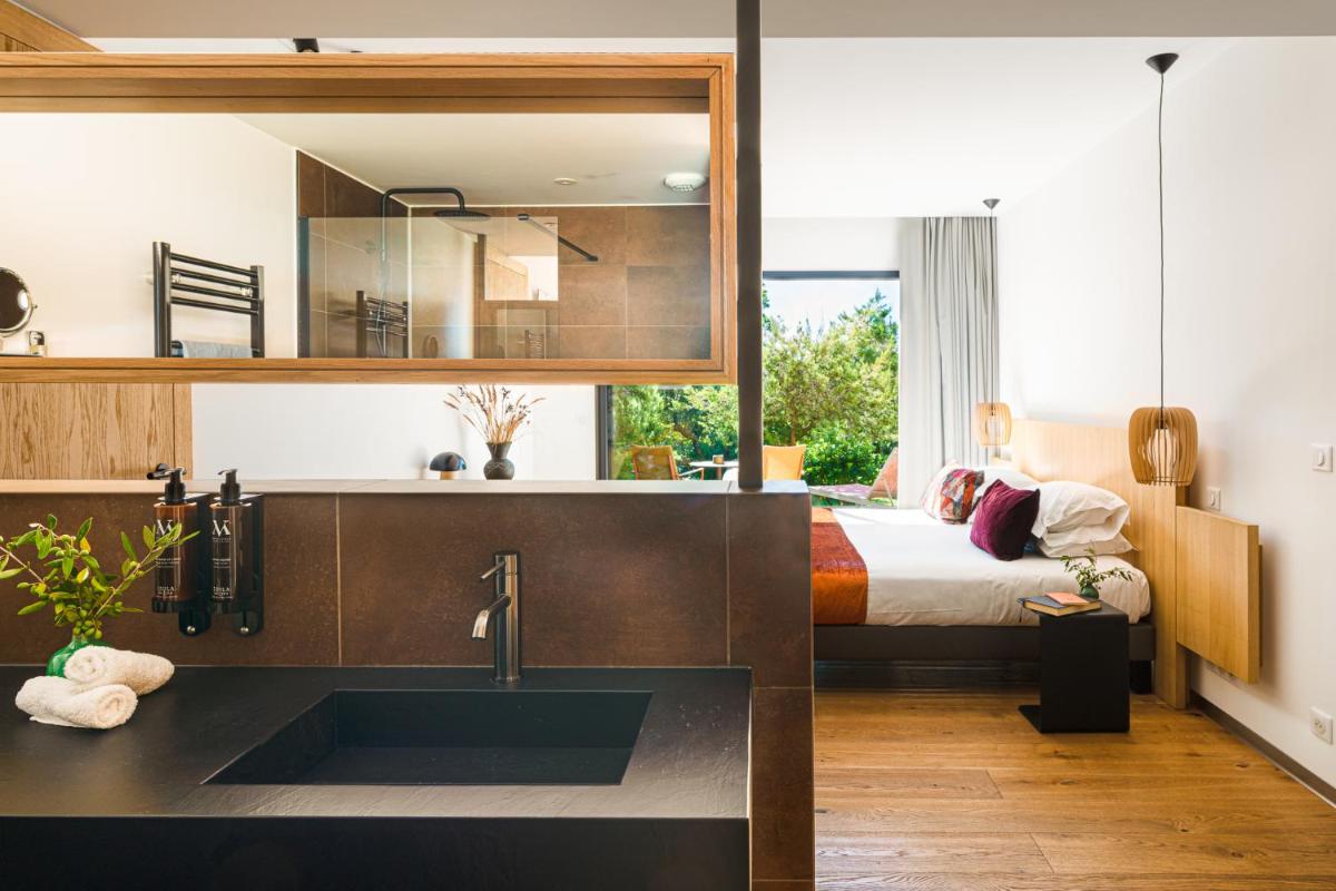La salle de bains est pourvue d'un lavabo et d'un lit dans la chambre. dans l'établissement Hôtel & Spa Version Maquis Citadelle, à Bonifacio La salle de bains est pourvue d'un lavabo et d'un lit dans la chambre. dans l'établissement Hôtel & Spa Version Maquis Citadelle, à Bonifacio